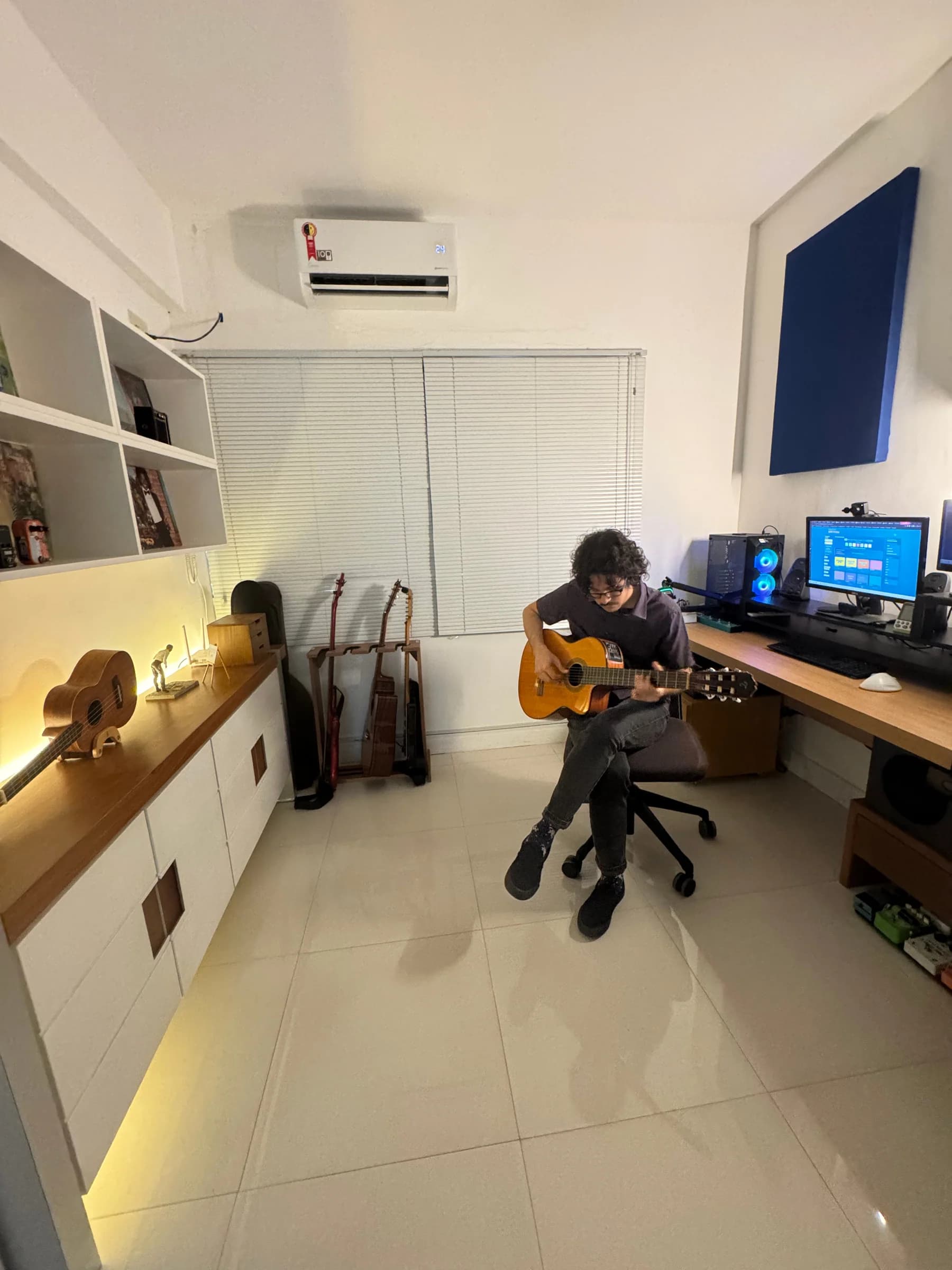 Vista ampla do estúdio com o Prof. Artur Guerra tocando violão